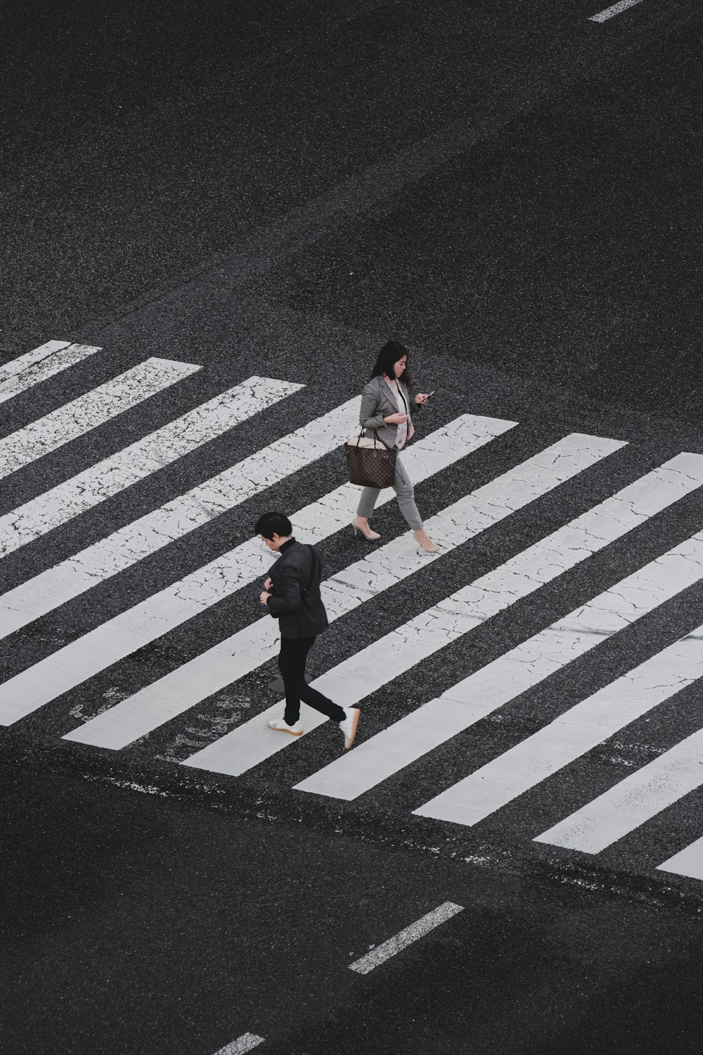 Fotografía aérea de un hombre y una mujer caminando por el carril peatonal durante el día