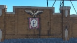 A brick wall with an emblem featuring an eagle perched on top. The emblem includes a shield with vertical red and white stripes and a central blue 'P'.