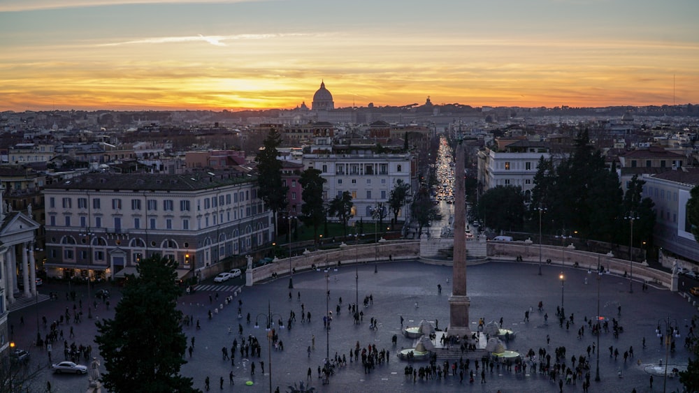 aerial photography of people standing in park near city buildings under orange sunset