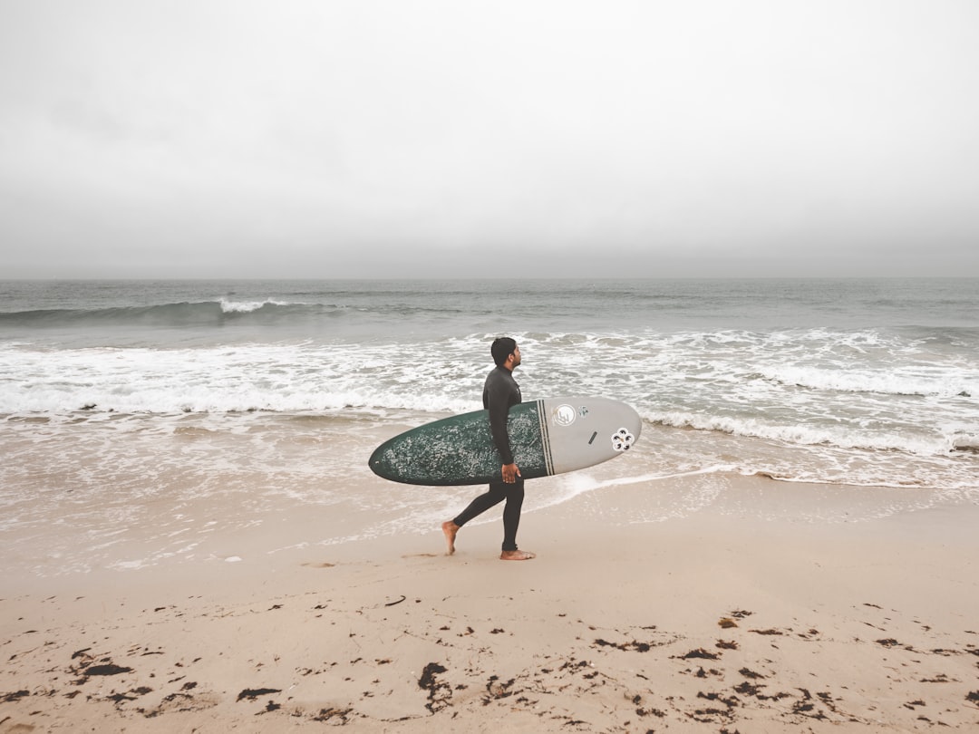 man holding surf board on seashore during daytime