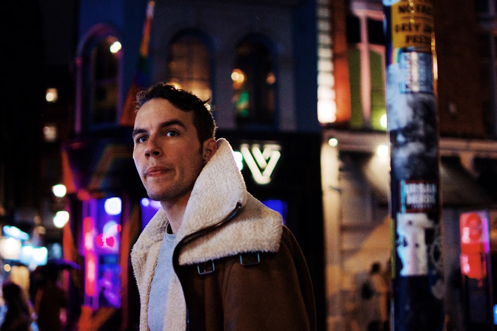 man in brown jacket standing beside building