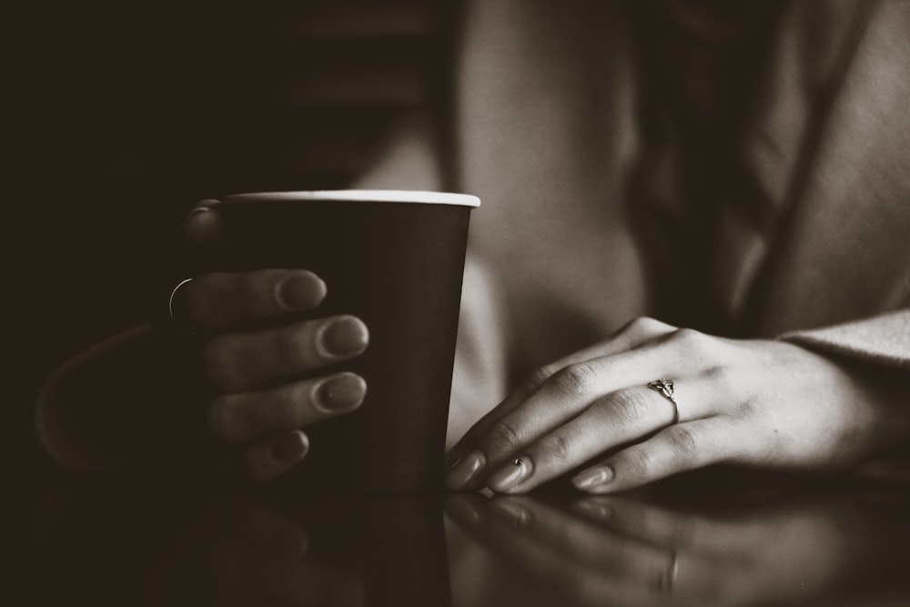 woman holding black coffee cup