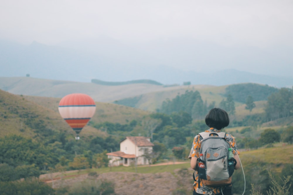 woman carrying backpack standing in open field