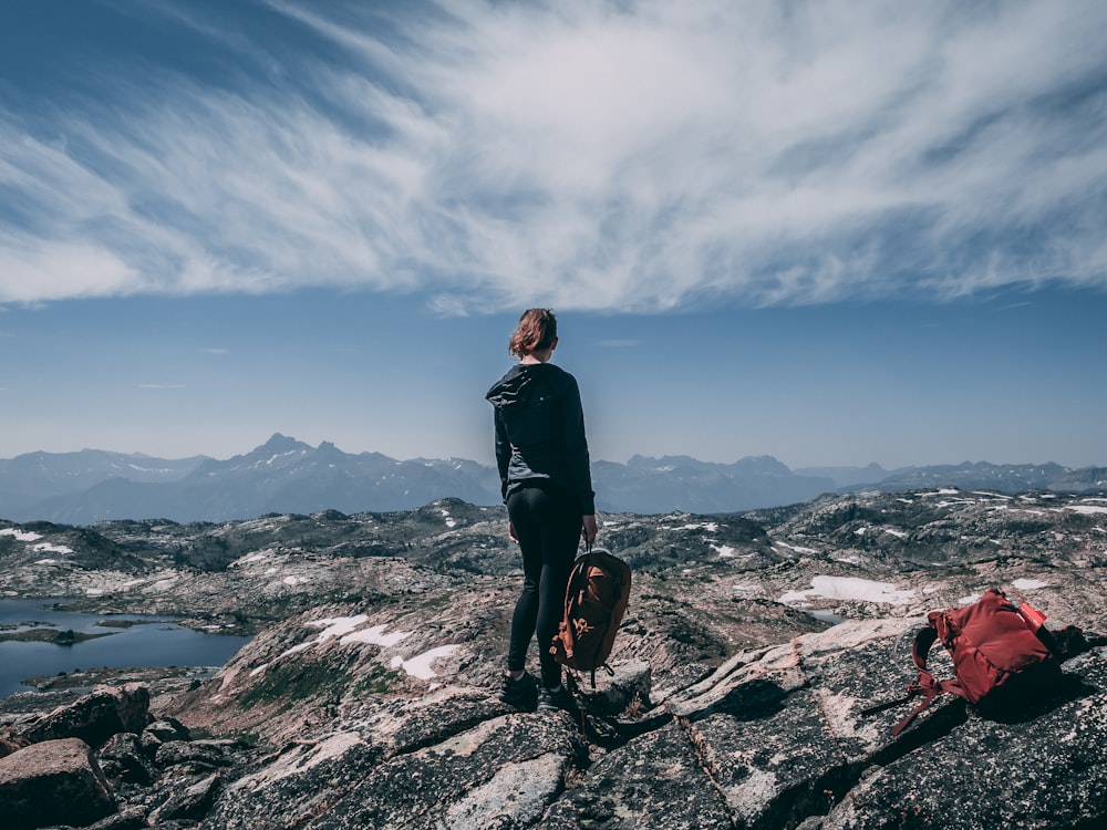 woman standing on rock while holding back under white sky