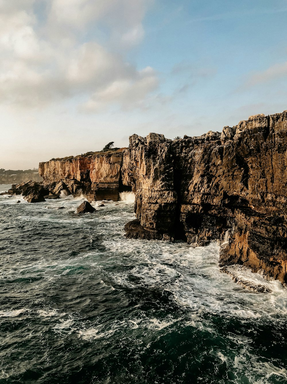 blue sea beside brown cliff under blue sky