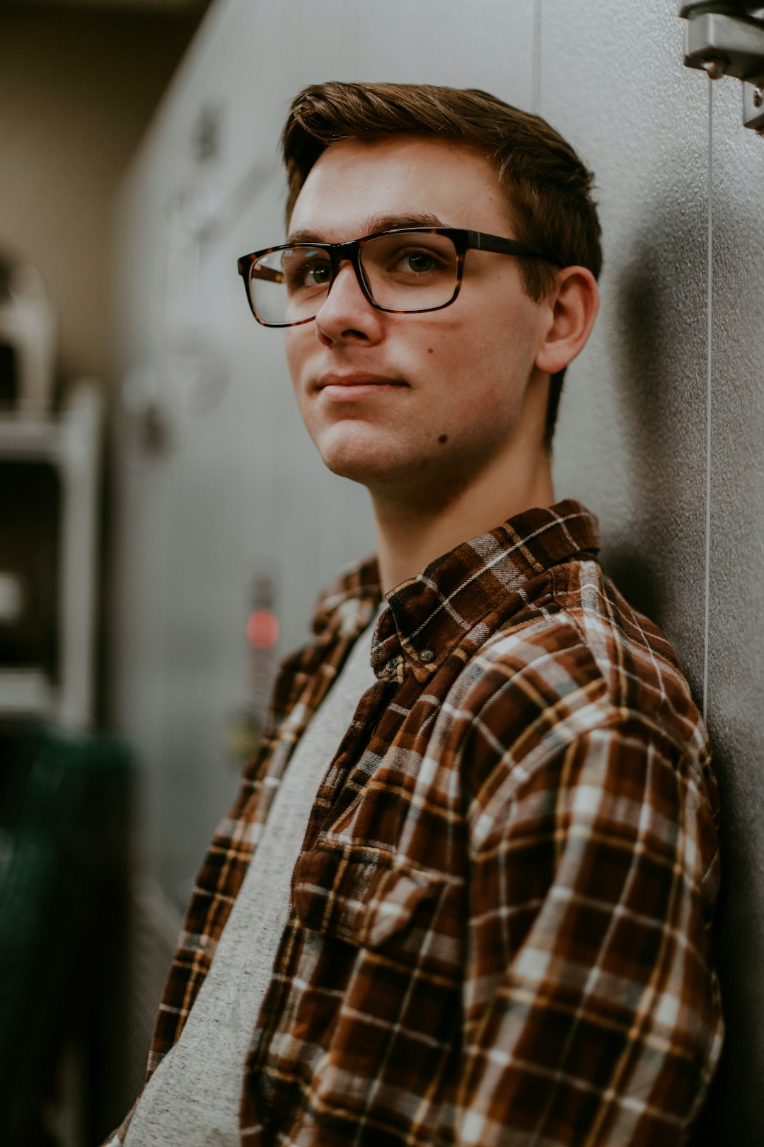 man wearing eyeglasses while leaning on wall