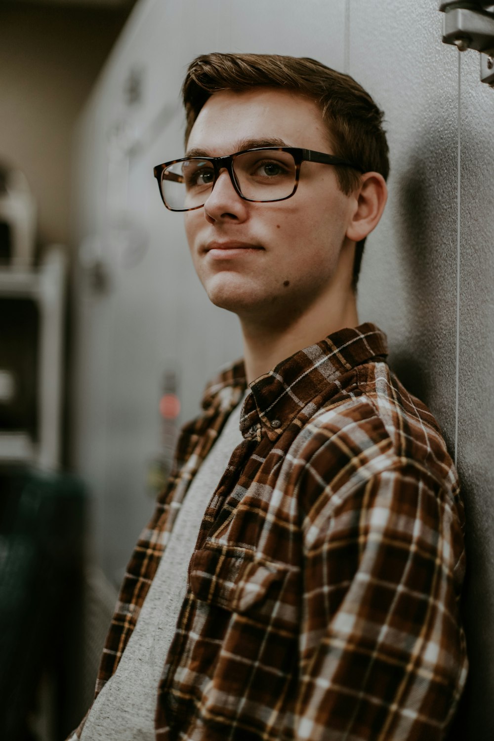man wearing eyeglasses while leaning on wall