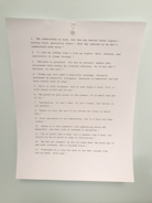 A piece of white paper is pinned to a light blue wall with a clear thumbtack. The paper contains a list of typed quotes, numbered from 1 to 13, each with a unique philosophical or motivational message.