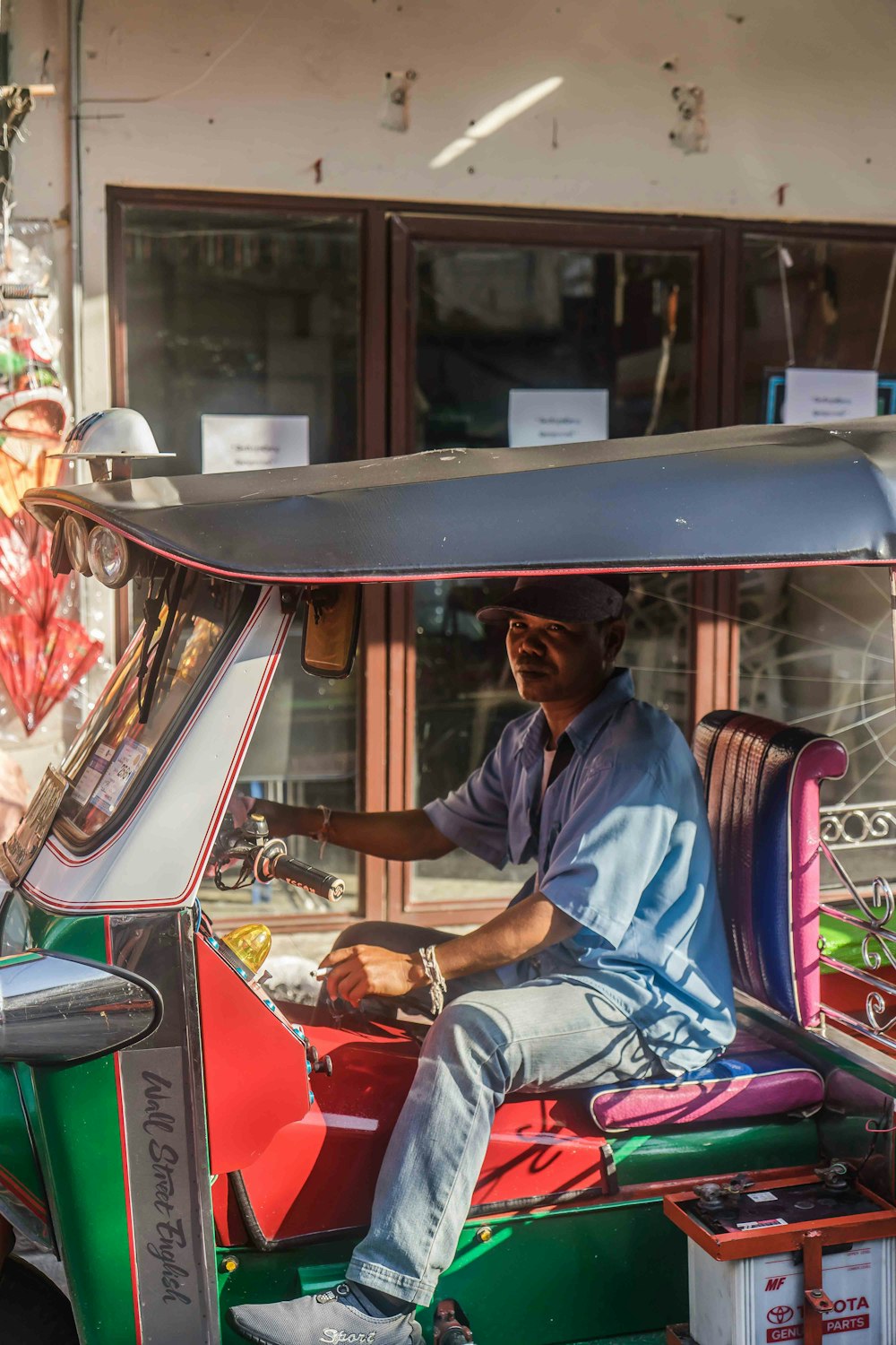 man riding autorickshaw beside concrete building