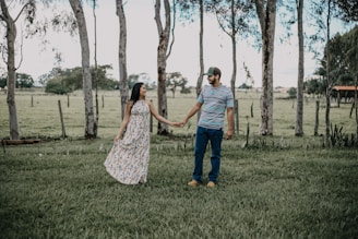 A happy couple standing beside their plot, surrounded by open land and trees.