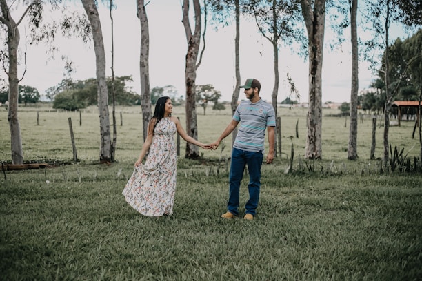 A happy couple standing beside their plot, surrounded by open land and trees.