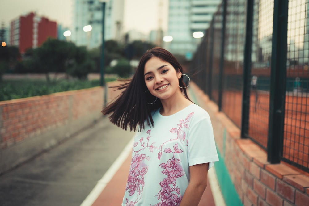selective focus photography of smiling woman wearing white and pink floral t-shirt