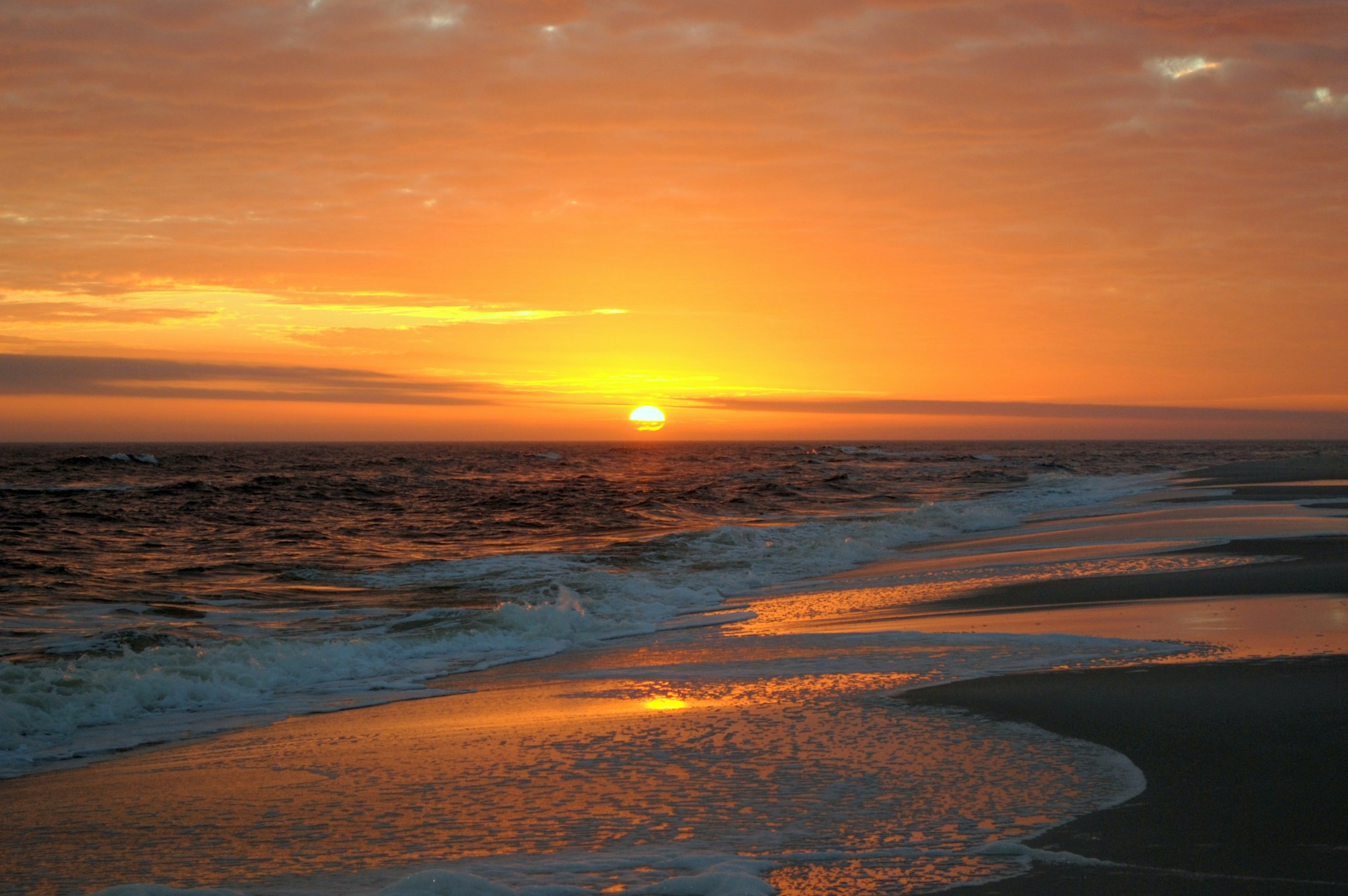 A breathtaking view of a serene beach at sunset, featuring soft waves and golden sand.