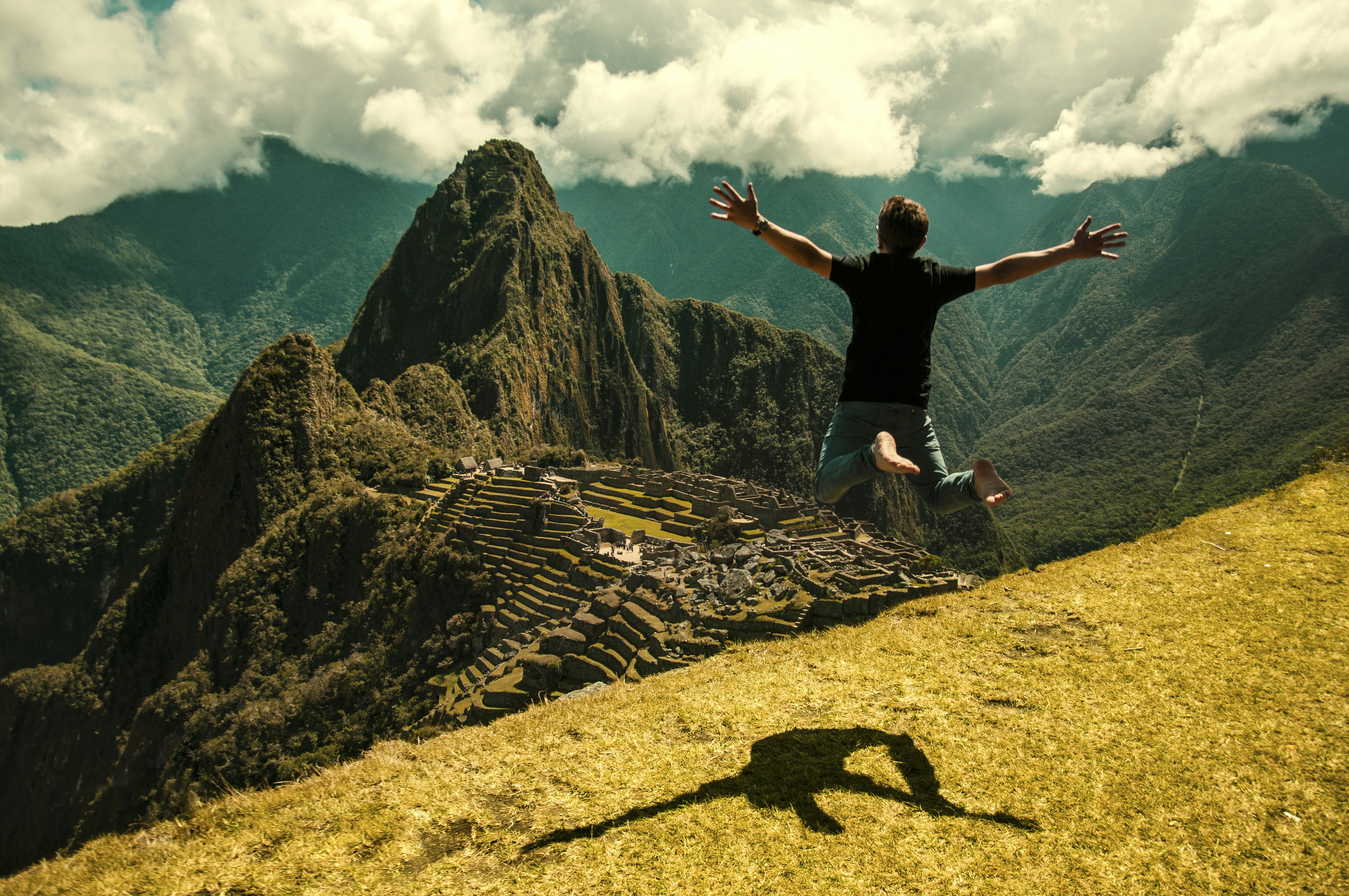 man jumping in green open field peru zoom background