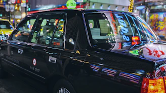 A gleaming black limousine parked under city lights, ready for a night out.