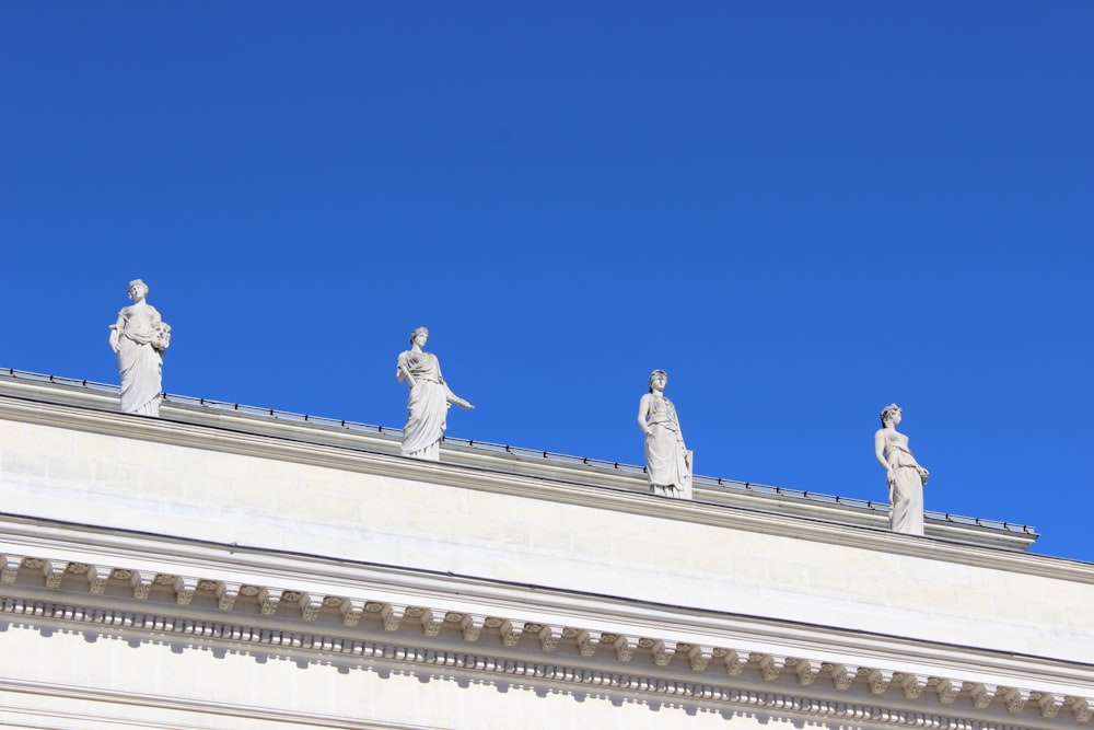 Quatre statues en béton blanc sous un ciel bleu clair