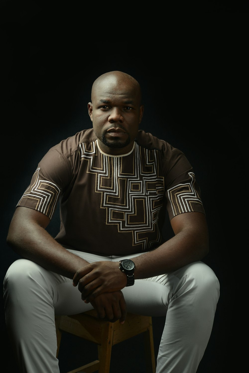 man in brown and white shirt sitting on chair