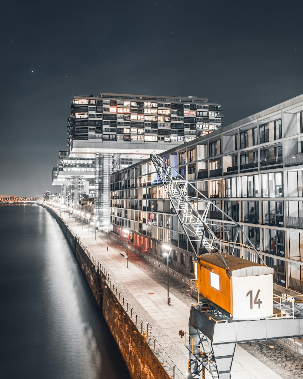 gray glass building beside body of water during night time