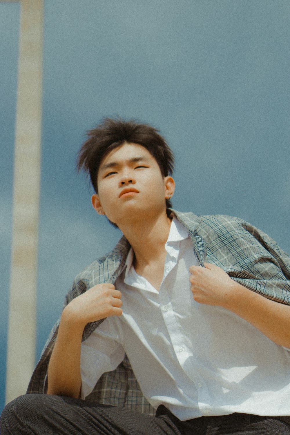 a young man sitting on the ground with his shirt open