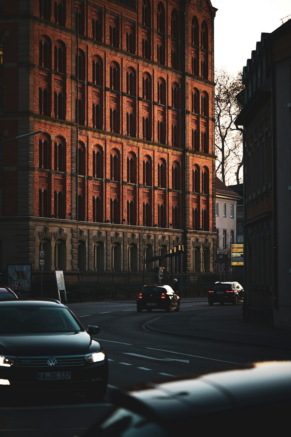 Autos, die auf der Straße an dem hohen braunen Gebäude vorbeifahren