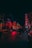 A vibrant urban street scene at night, illuminated by numerous neon signs in shades of red and blue. People walk along the dimly lit street, with vehicles parked on the sides. The atmosphere is bustling yet moody, characteristic of a lively nightlife environment.
