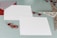 Two blank white cards are placed on a light blue background. Beside them is a red envelope with a striped flap. Decorative red gems and a sparkling silver star-shaped ornament are arranged around the cards, giving a festive appearance.