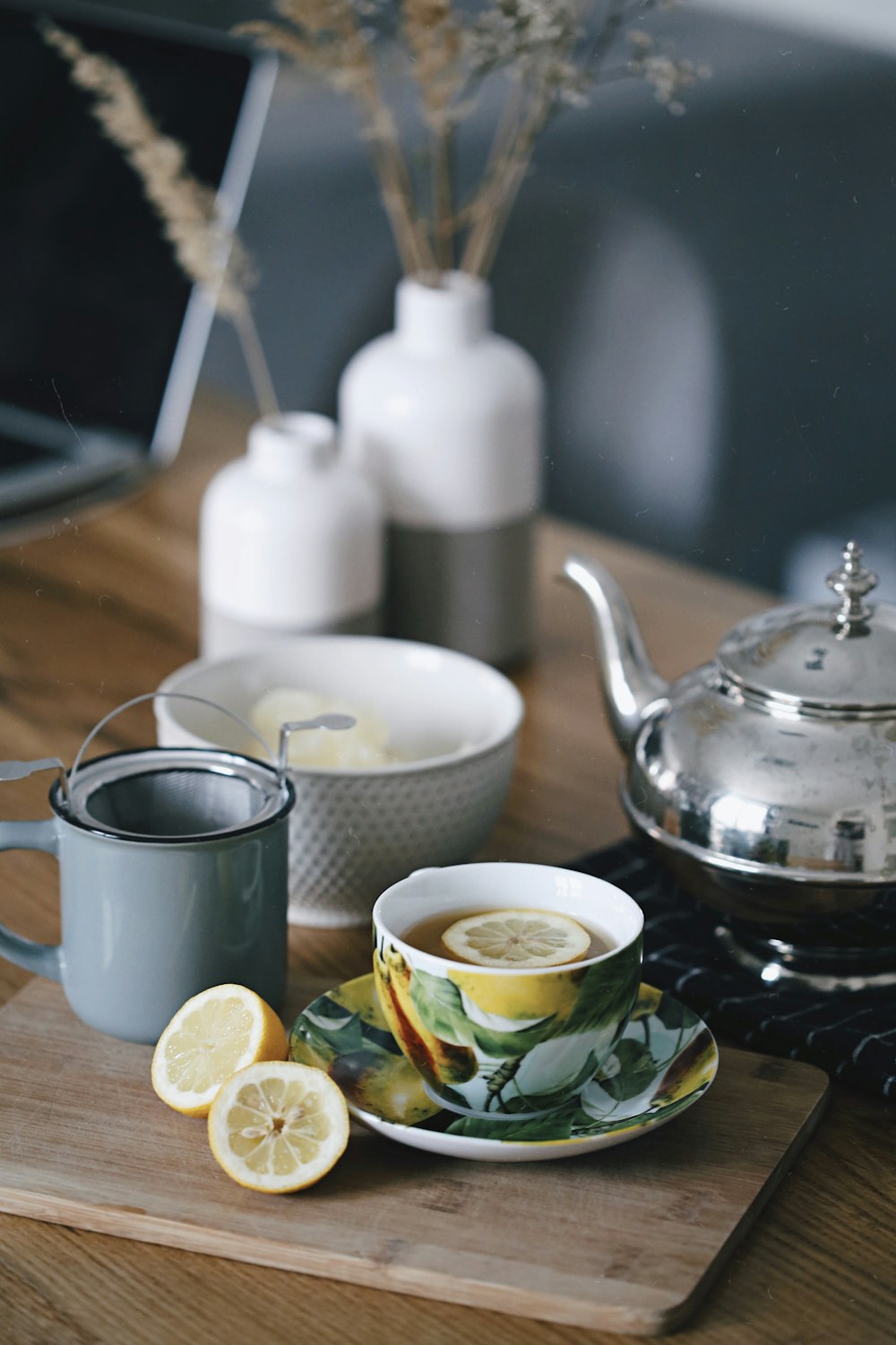 Teiera grigia accanto alla tazza piena di tè e limone sopra il tavolo