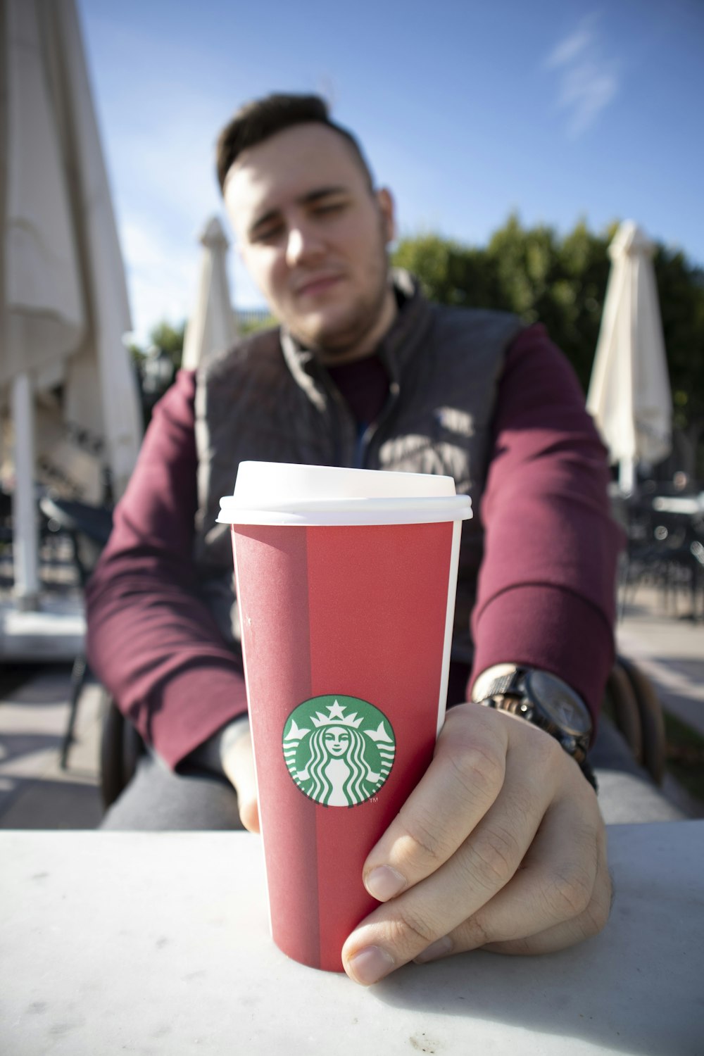 person putting red Starbucks disposable cup on table