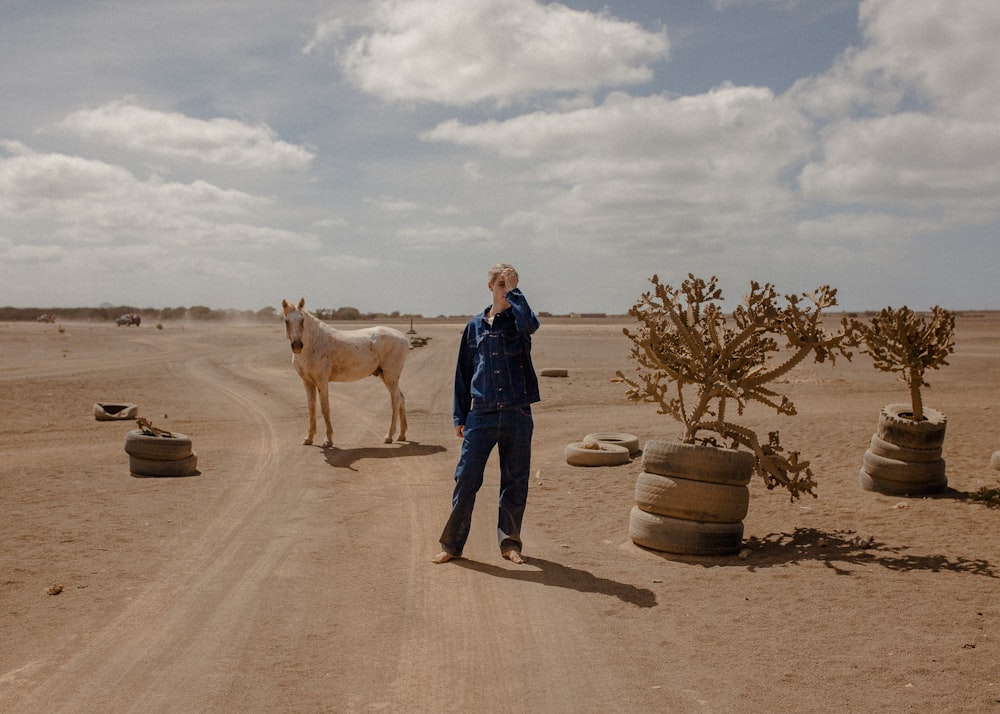 man standing beside horse and plants