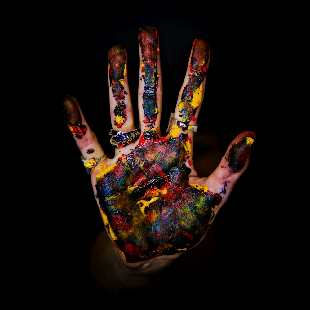 Persona che mostra le mani con i dipinti multicolori