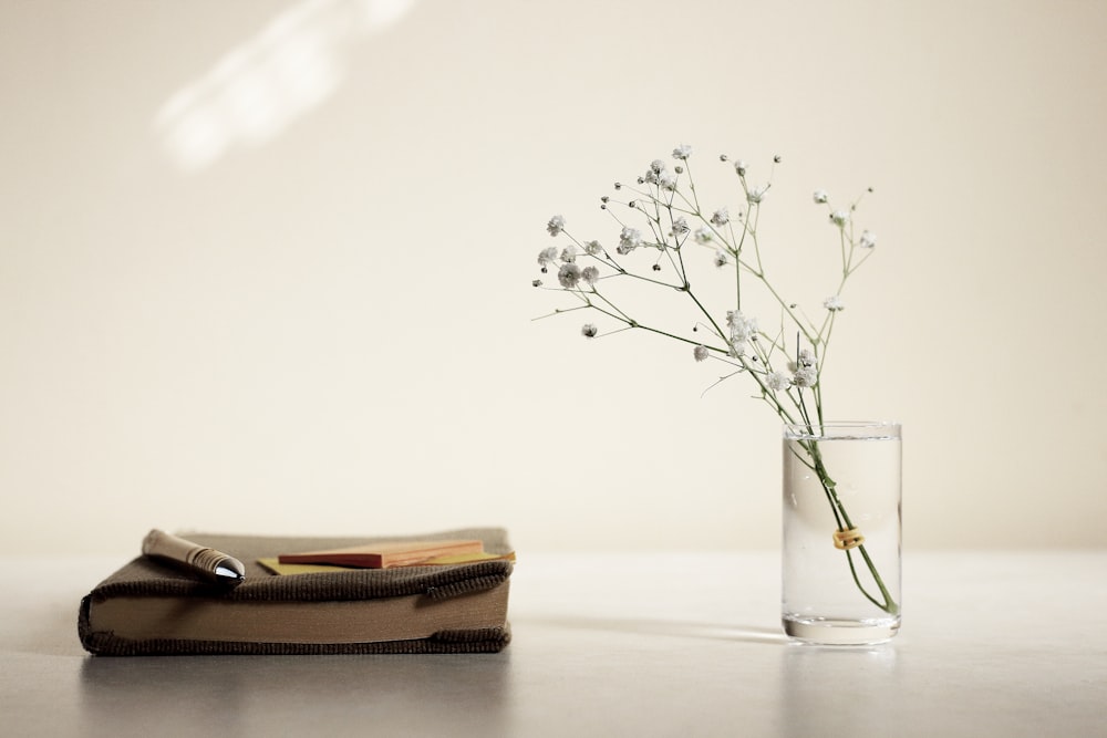 white petaled flower in glass vase beside book