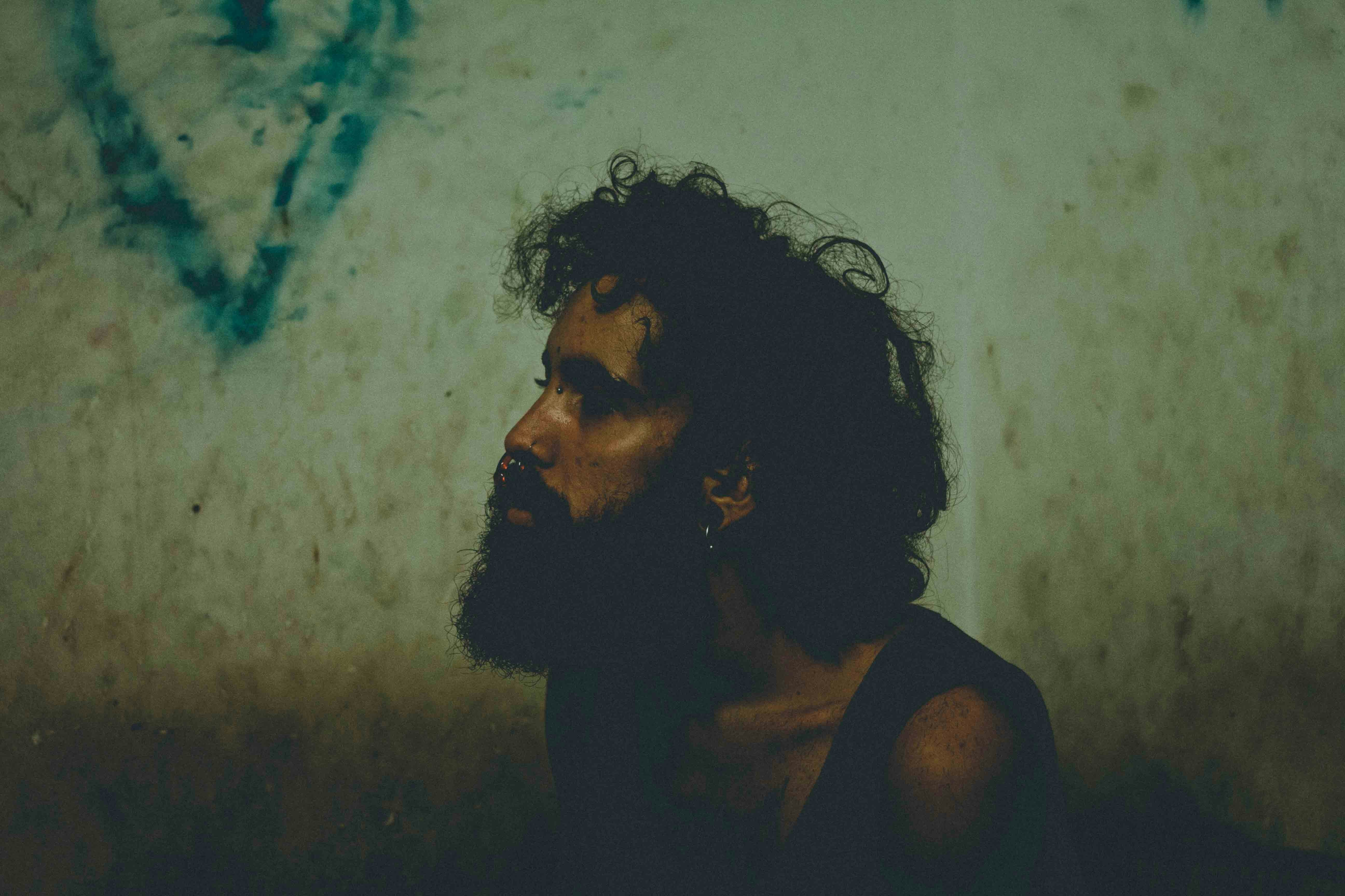 man sitting beside white wall