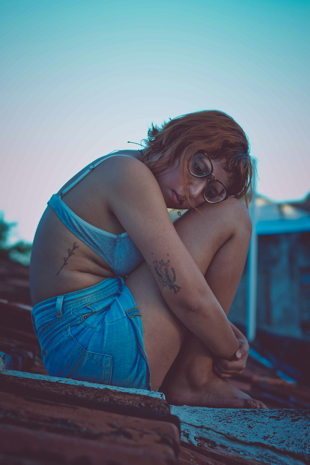 selective focus photography of woman sitting on roof during daytime