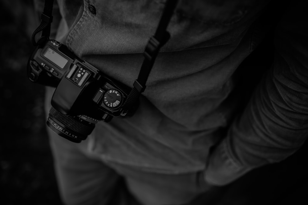 personne en chemise habillée avec photographie en niveaux de gris de l’appareil photo reflex numérique noir