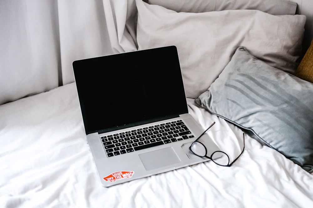 eyeglasses and MacBook on mattress