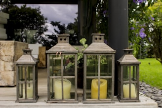 A rustic lantern placed on a wooden table, surrounded by greenery.
