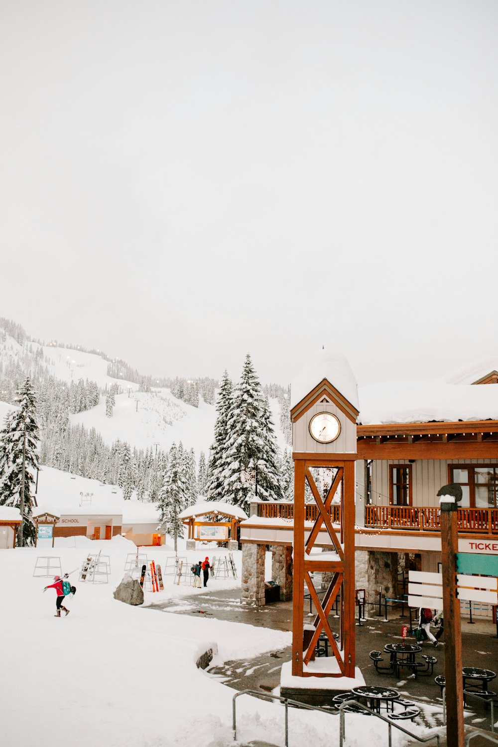 people standing in field covered with snow near white and brown wooden house