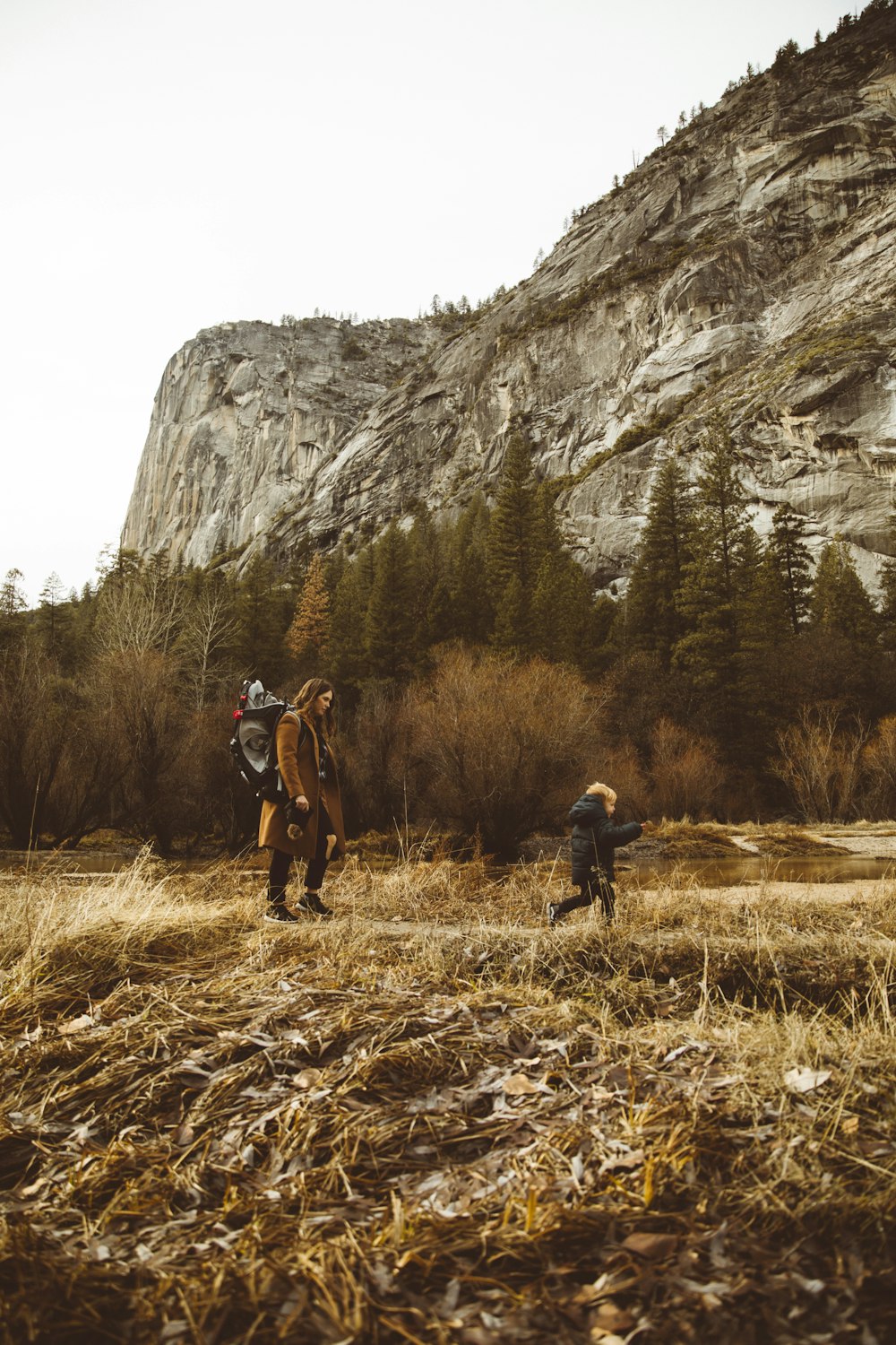 woman and boy waking at walkway beside mountain