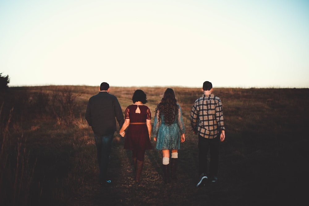 two women and two men walking at green grass field