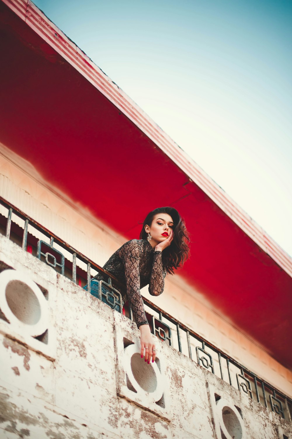 woman wearing sea through shirt leaning on building's railings