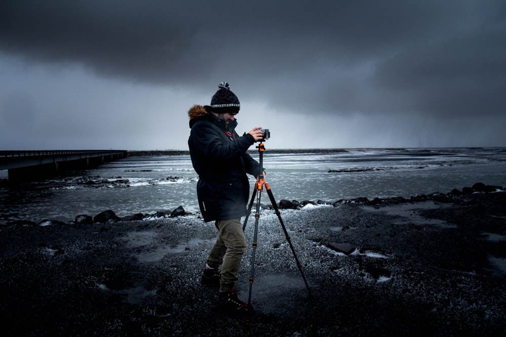 바다에서 삼각대를 사용하여 사진을 찍는 남자