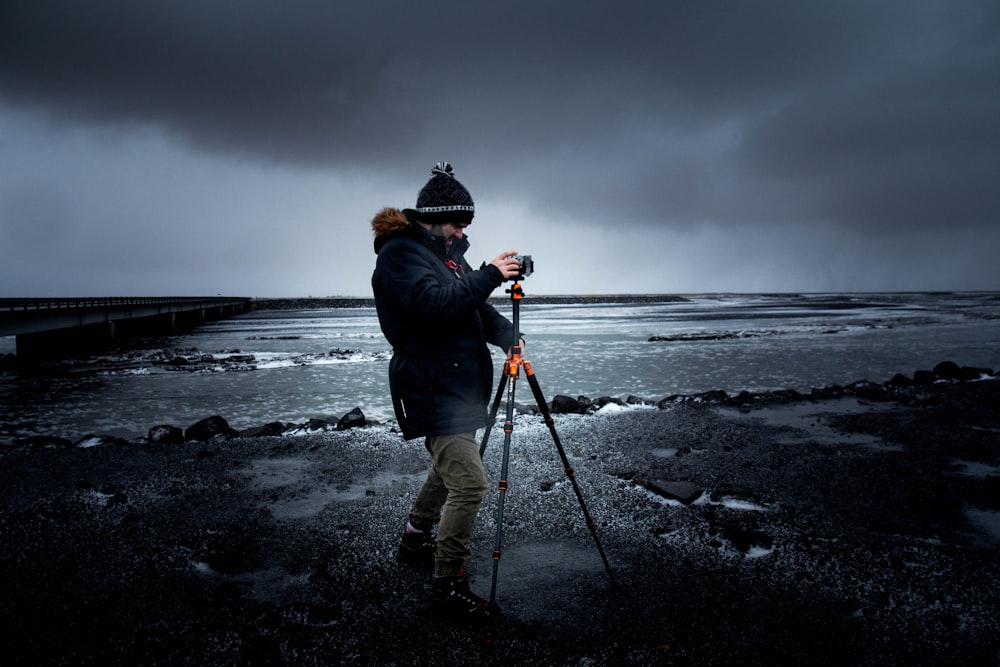 man taking photo using tripod at sea