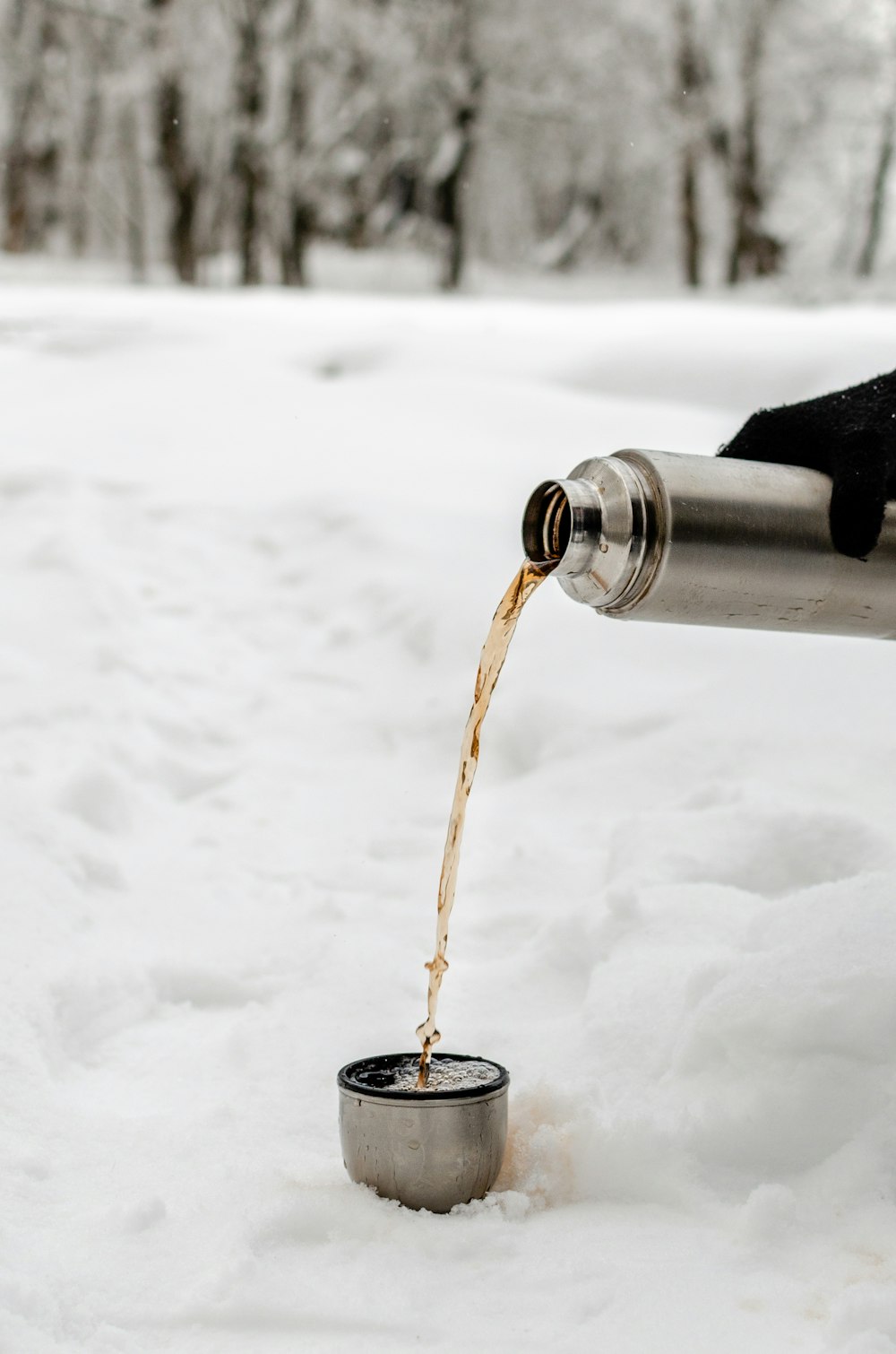 persona che versa il coperchio del pallone sottovuoto sul pavimento coperto di neve bianca