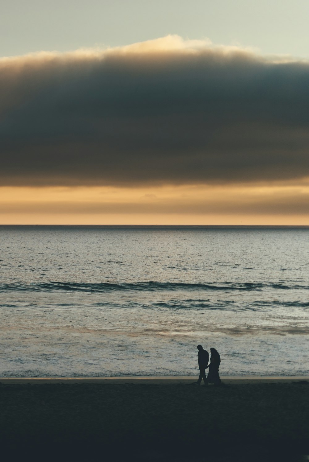 silueta del hombre y de la mujer de pie en la orilla del mar