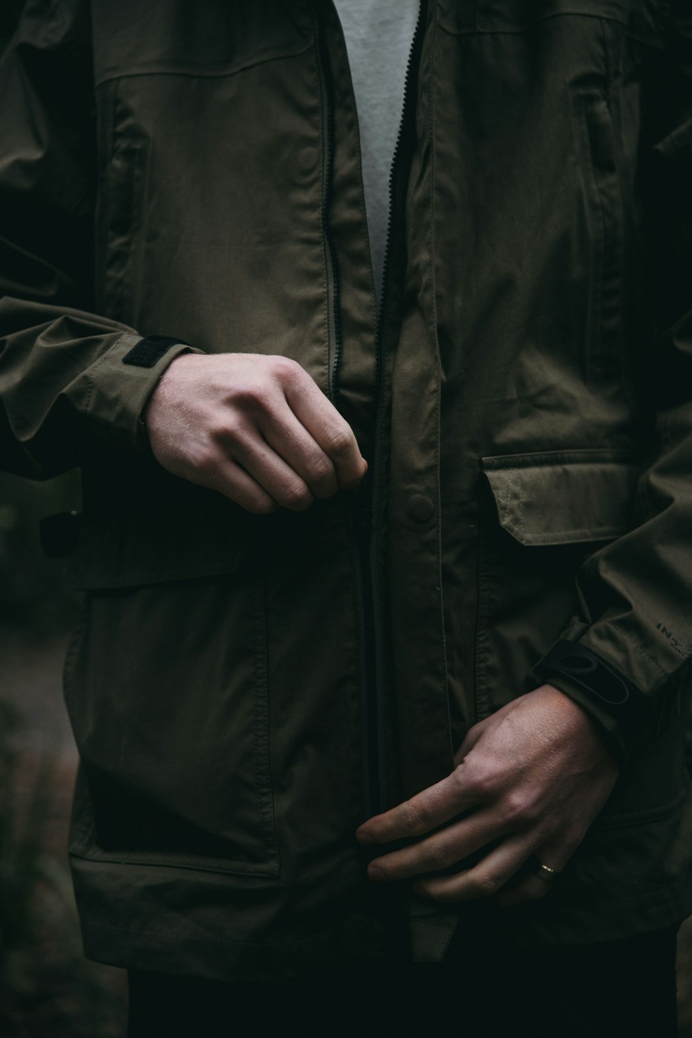 person wearing brown zip-up jacket about to close the zipper