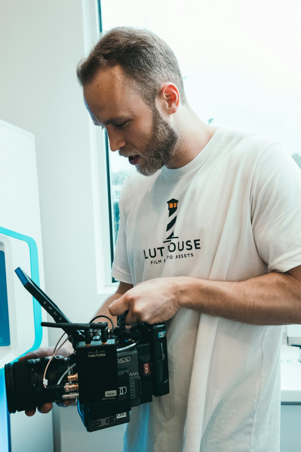 man in white crew-neck T-shirt using black video camera