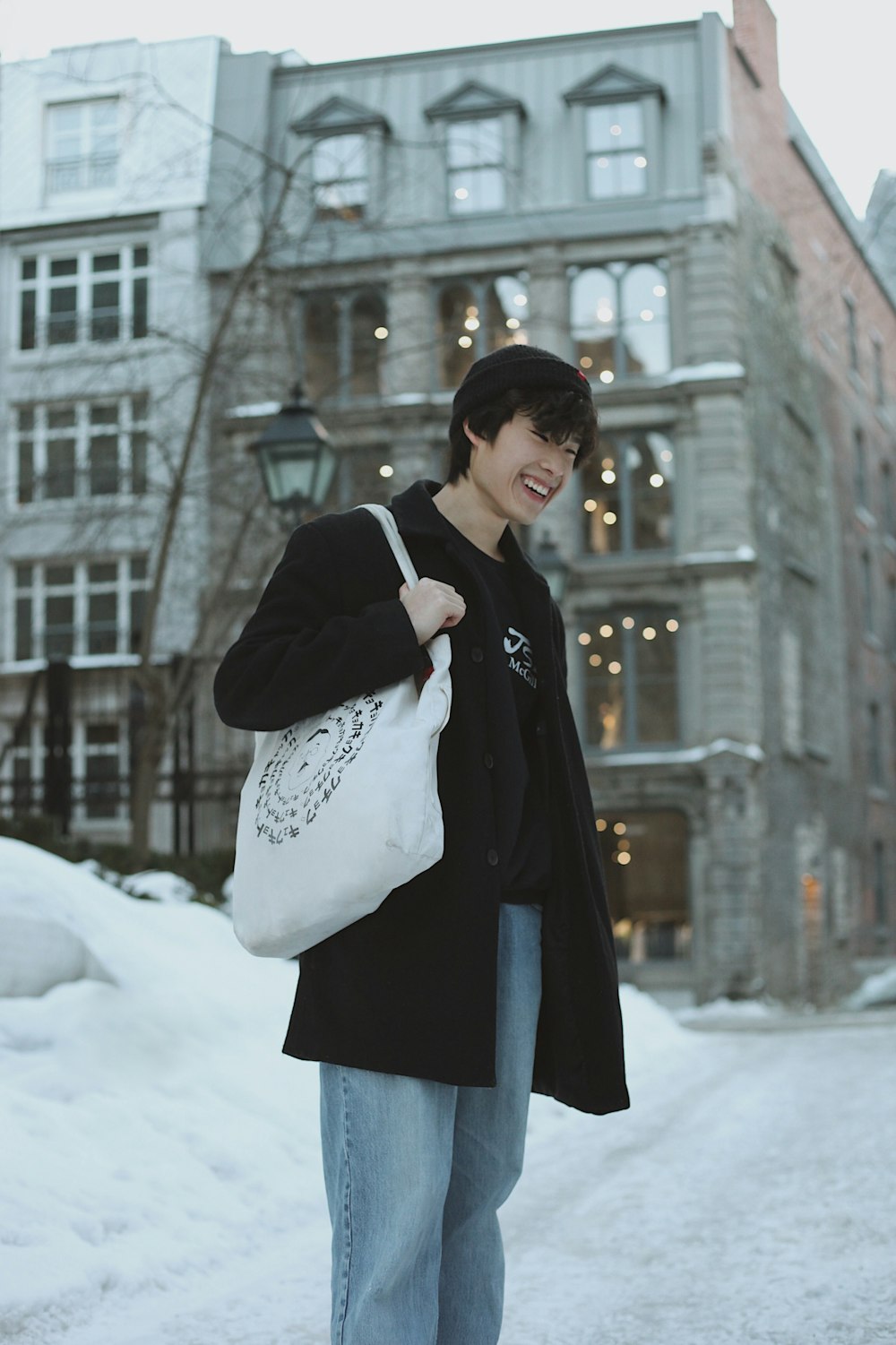 person wearing black coat clutching white bag at snowy street