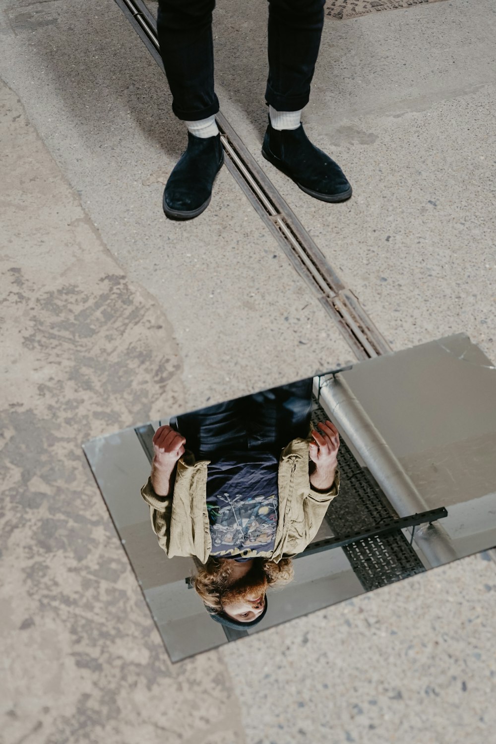 woman in brown jacket reflecting on mirror on floor