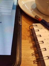 Close-up of a student taking notes while watching an online course on a tablet.