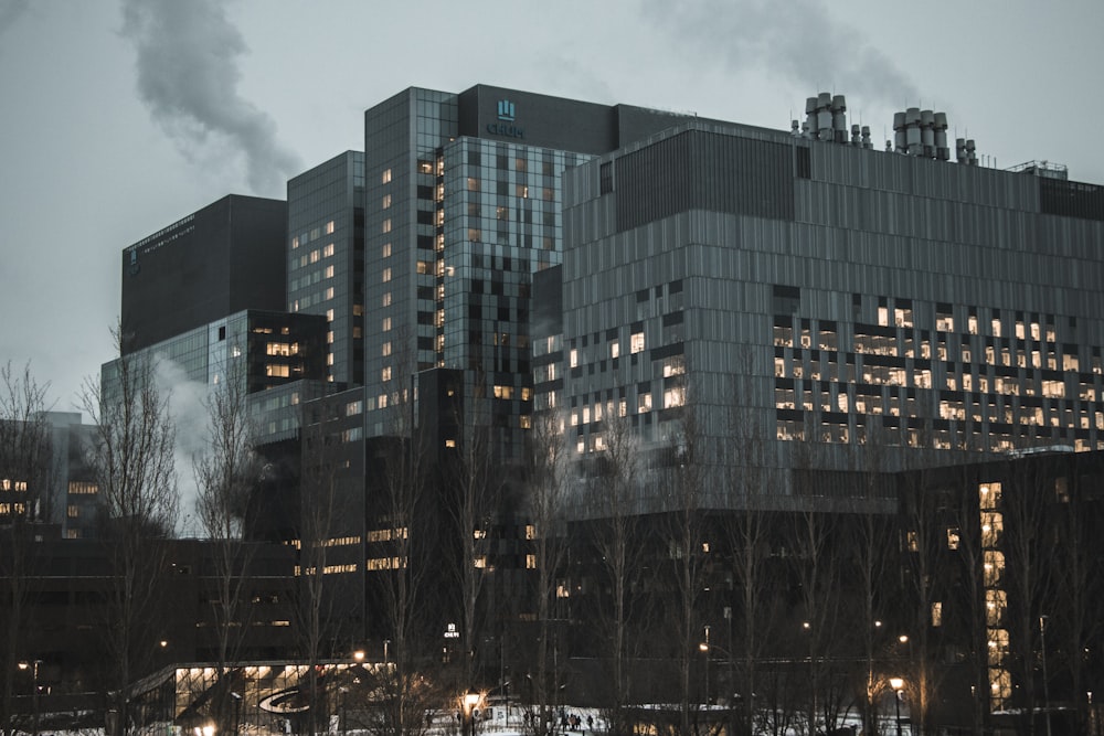 grey and black multi-storey concrete buildings with lights turned on under white sky